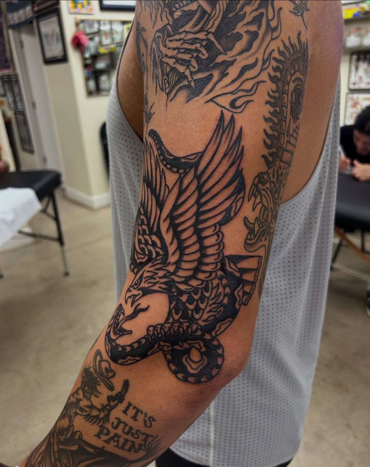 Tattooed arm showing a black and grey american traditional sleeve with an eagle.