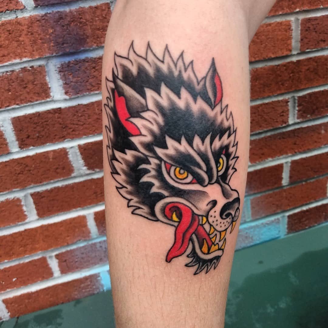 American traditional wolf head tattoo with bold outlines on a person's forearm