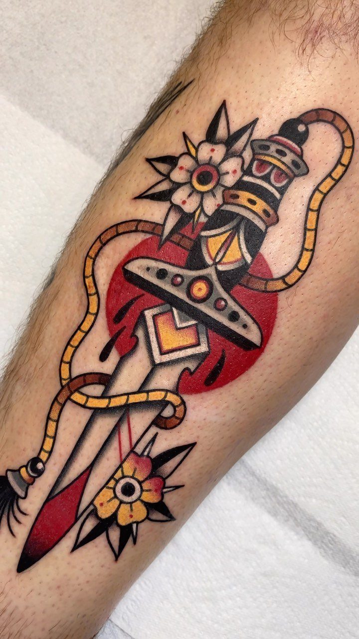 Dagger tattoo with rope and yellow flowers in American traditional style on skin