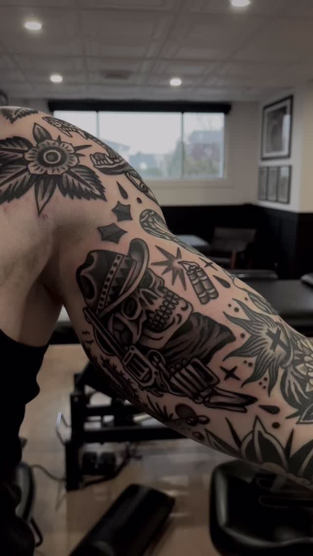 Skull tattoo wearing a cowboy hat on a person's muscular arm.
