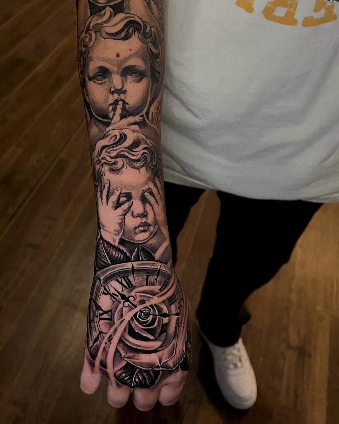 Tattoo of cherubs and a clock with a rose on a hand