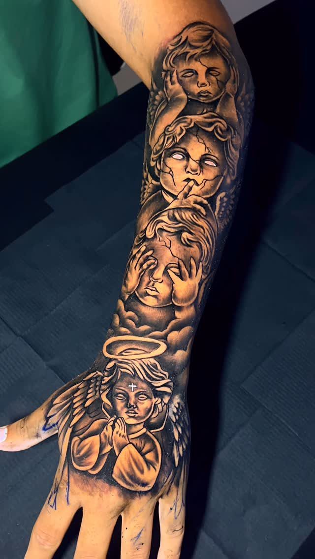 Cherub tattoo on a hand and forearm with a small cross on the forehead.