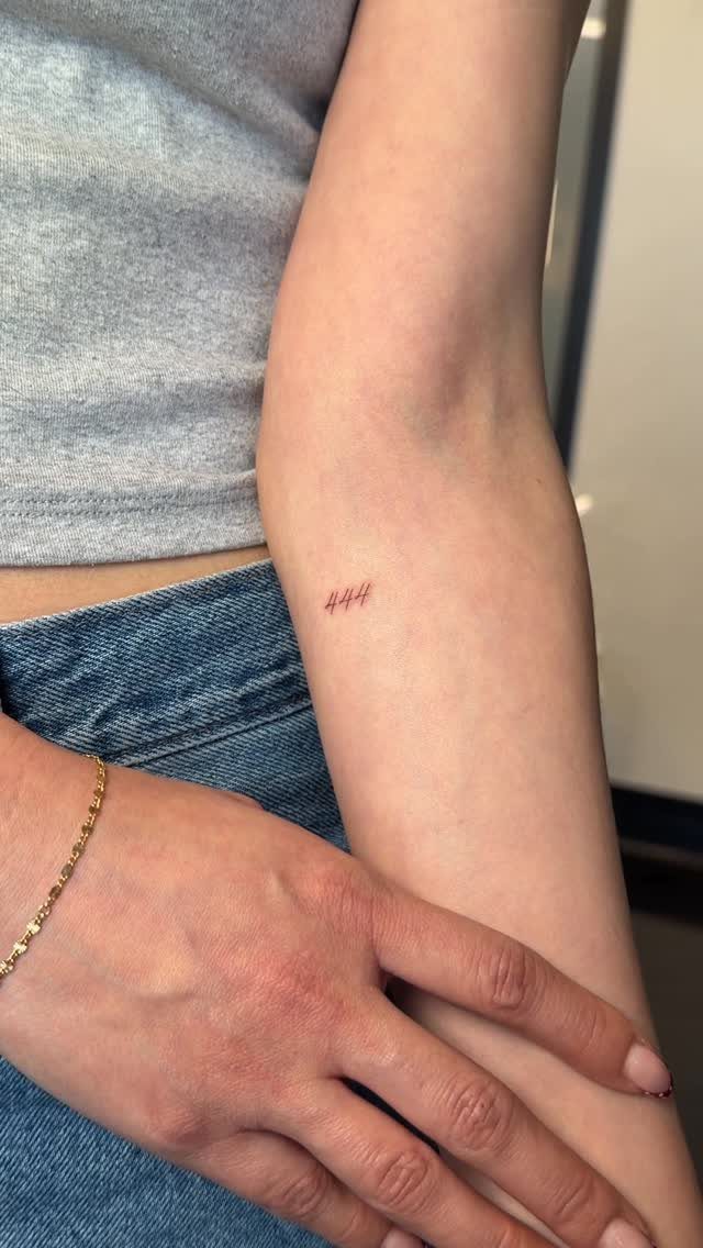 Small red 444 tattoo on the inner forearm of a person.