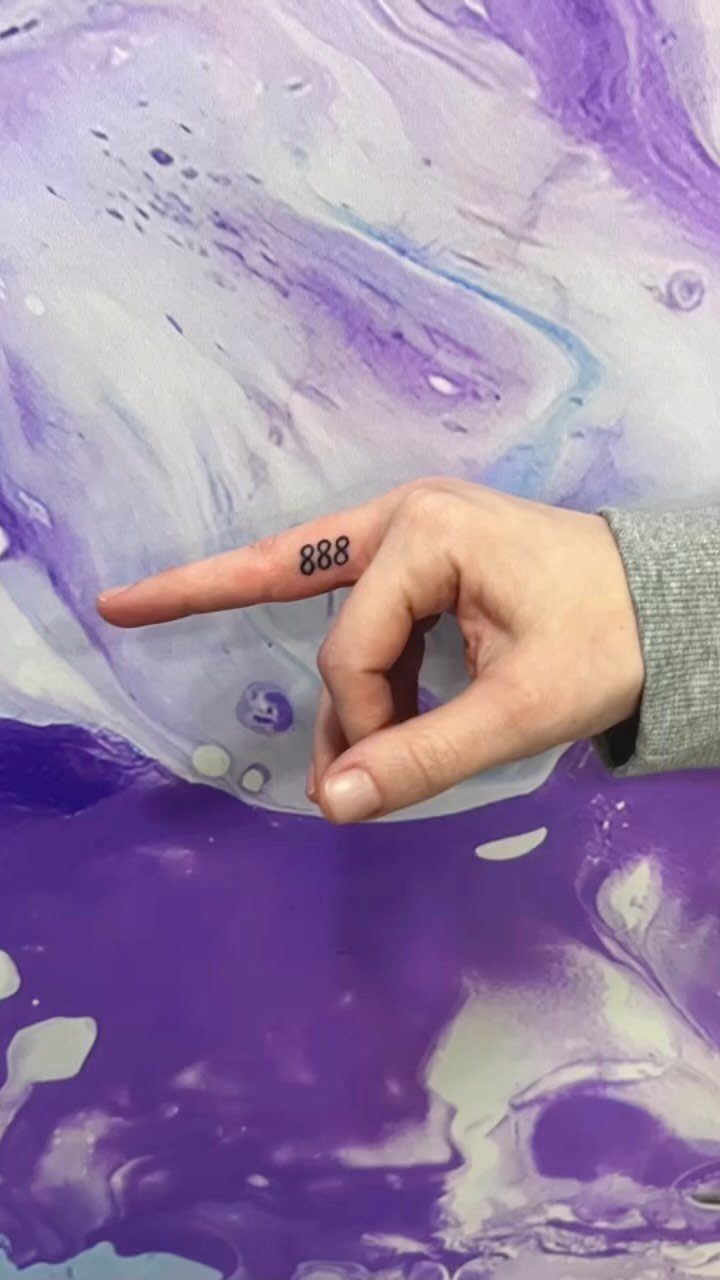 Hand with a small black 888 tattoo on the side of the index finger