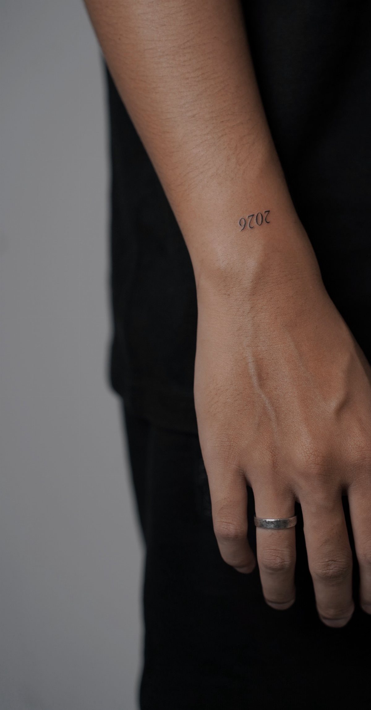 Small black tattoo of the number 2020 on a person's inner wrist