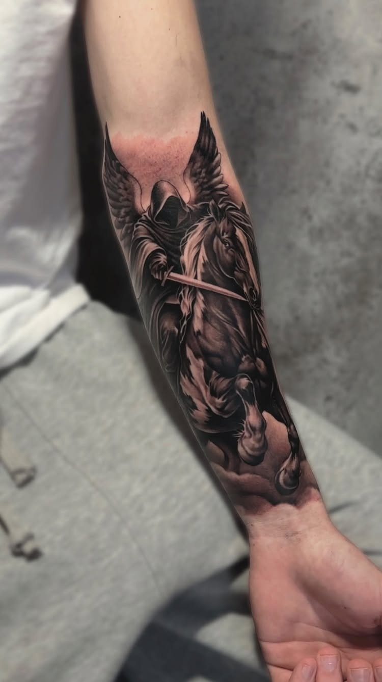Hooded winged figure on a horse tattoo on a person's forearm