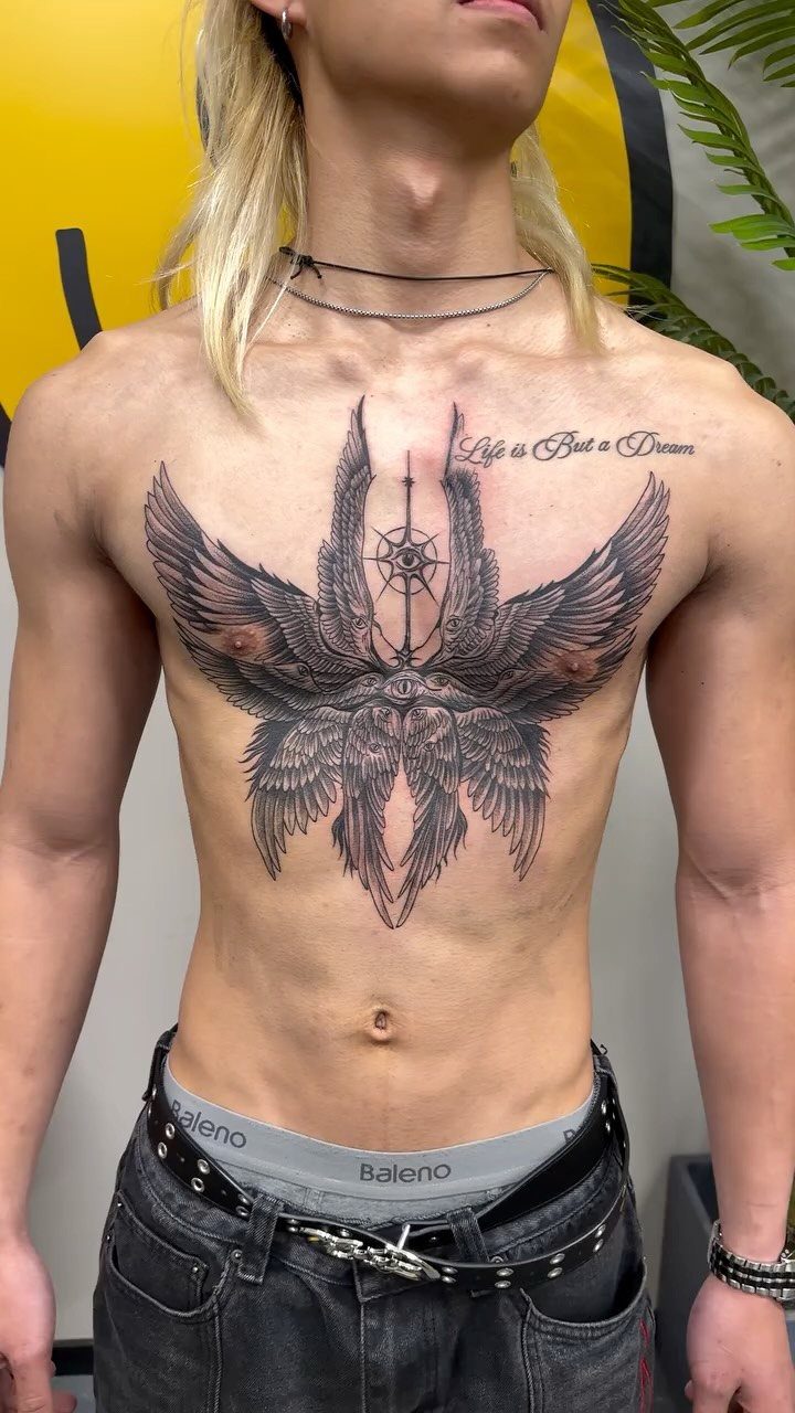Large black ink angel wings tattoo covering a person's chest and upper abdomen.