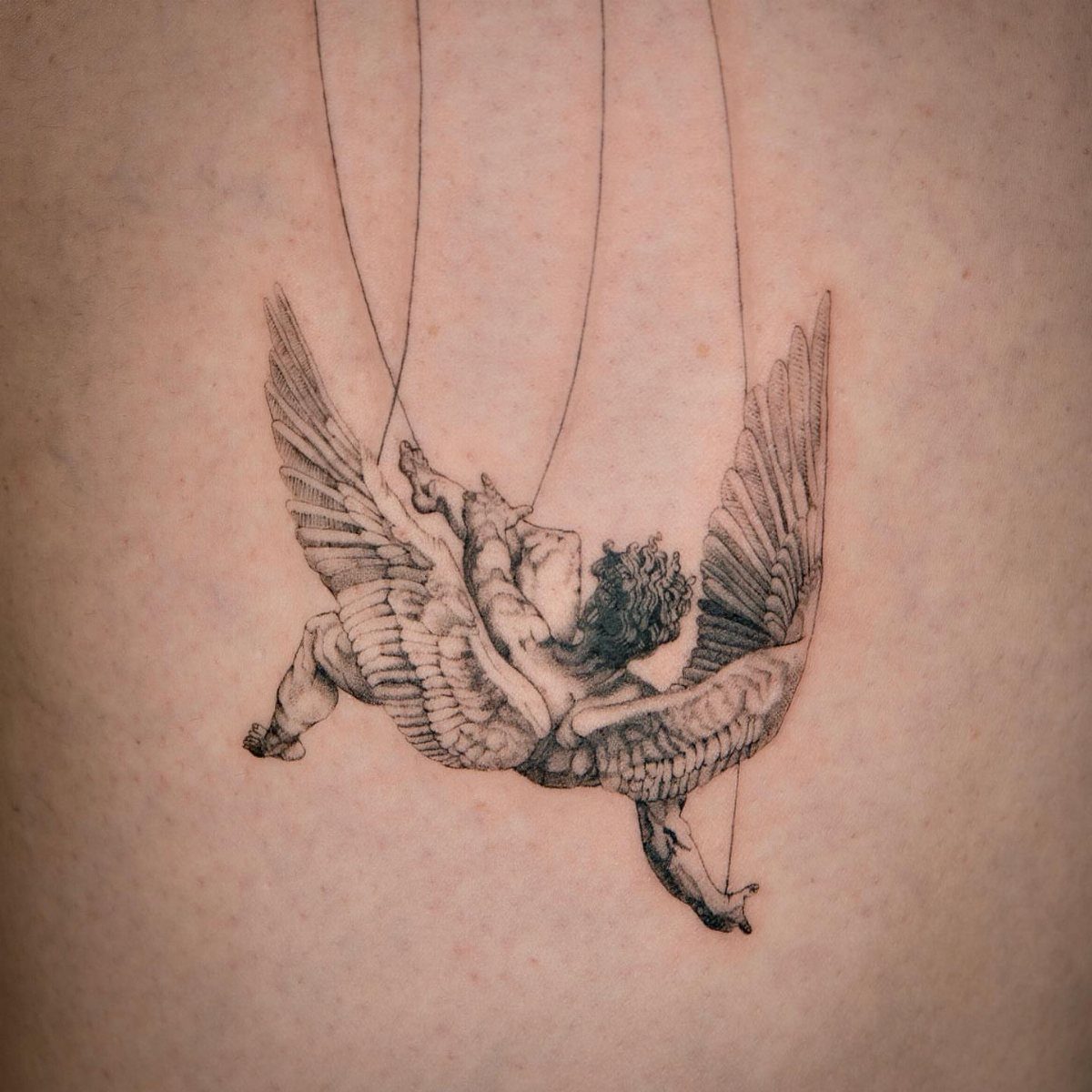 Marionette angel tattoo with wings and strings on a person's skin