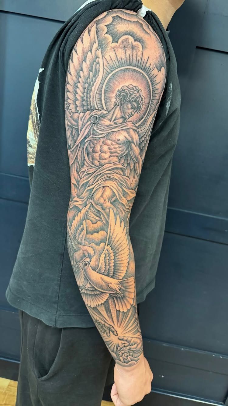 Full sleeve tattoo of a muscular angel with wings and a dove.