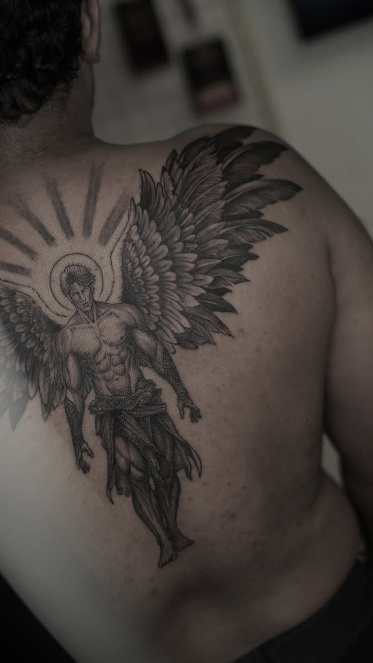 Muscular winged angel tattoo with a halo on a person's back