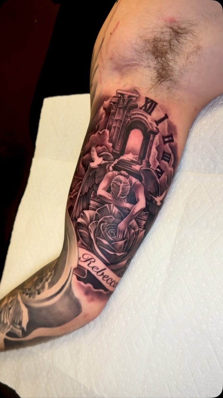 Black and grey memorial tattoo of a weeping angel with the name Rebecca.