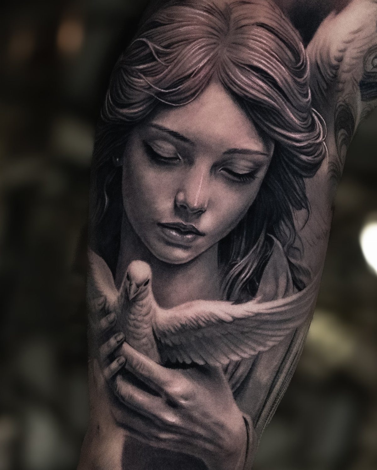 Detailed realism tattoo of a female angel holding a white dove on an arm