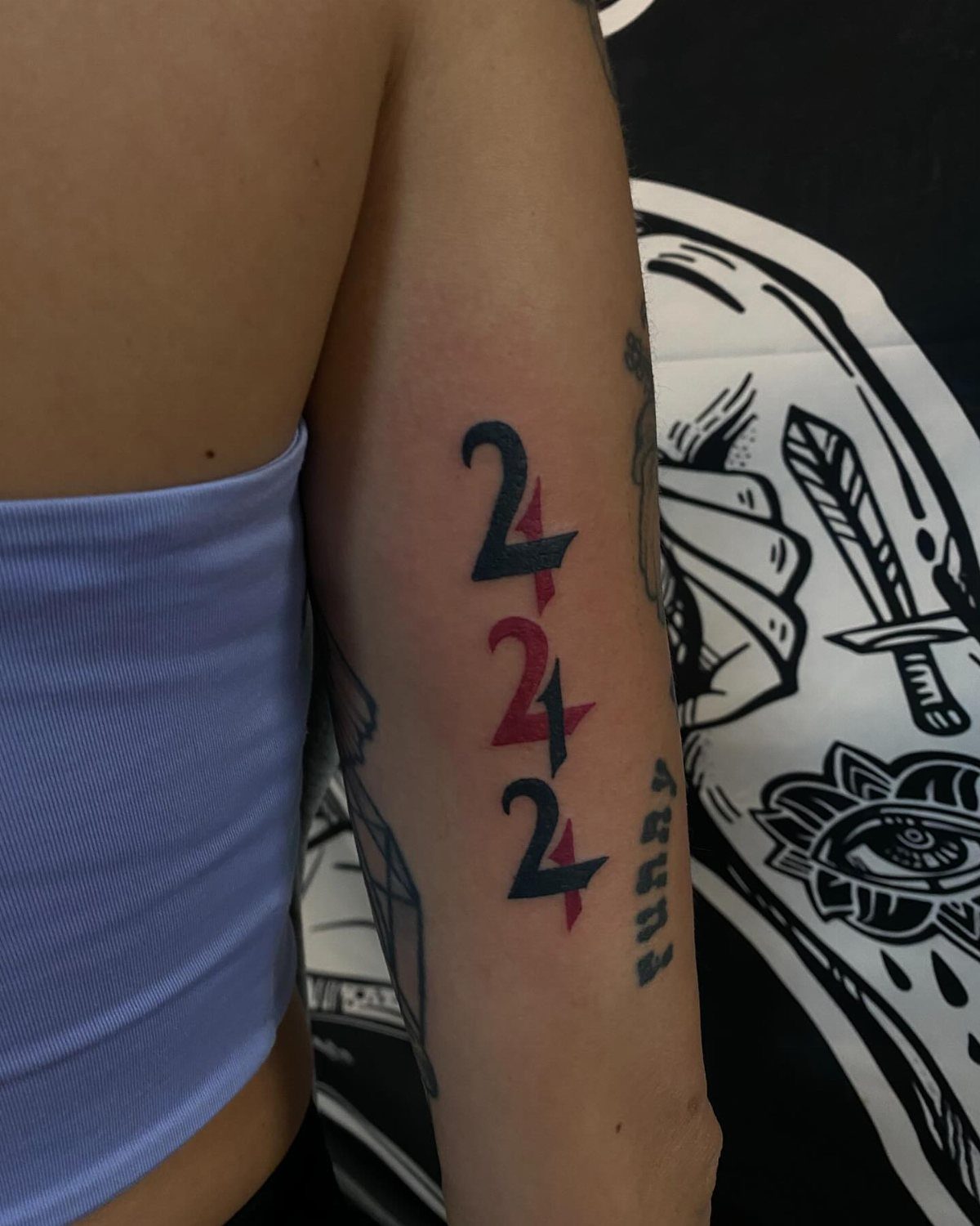 Vertical 222 angel numbers tattoo with blue and red gradient on an arm