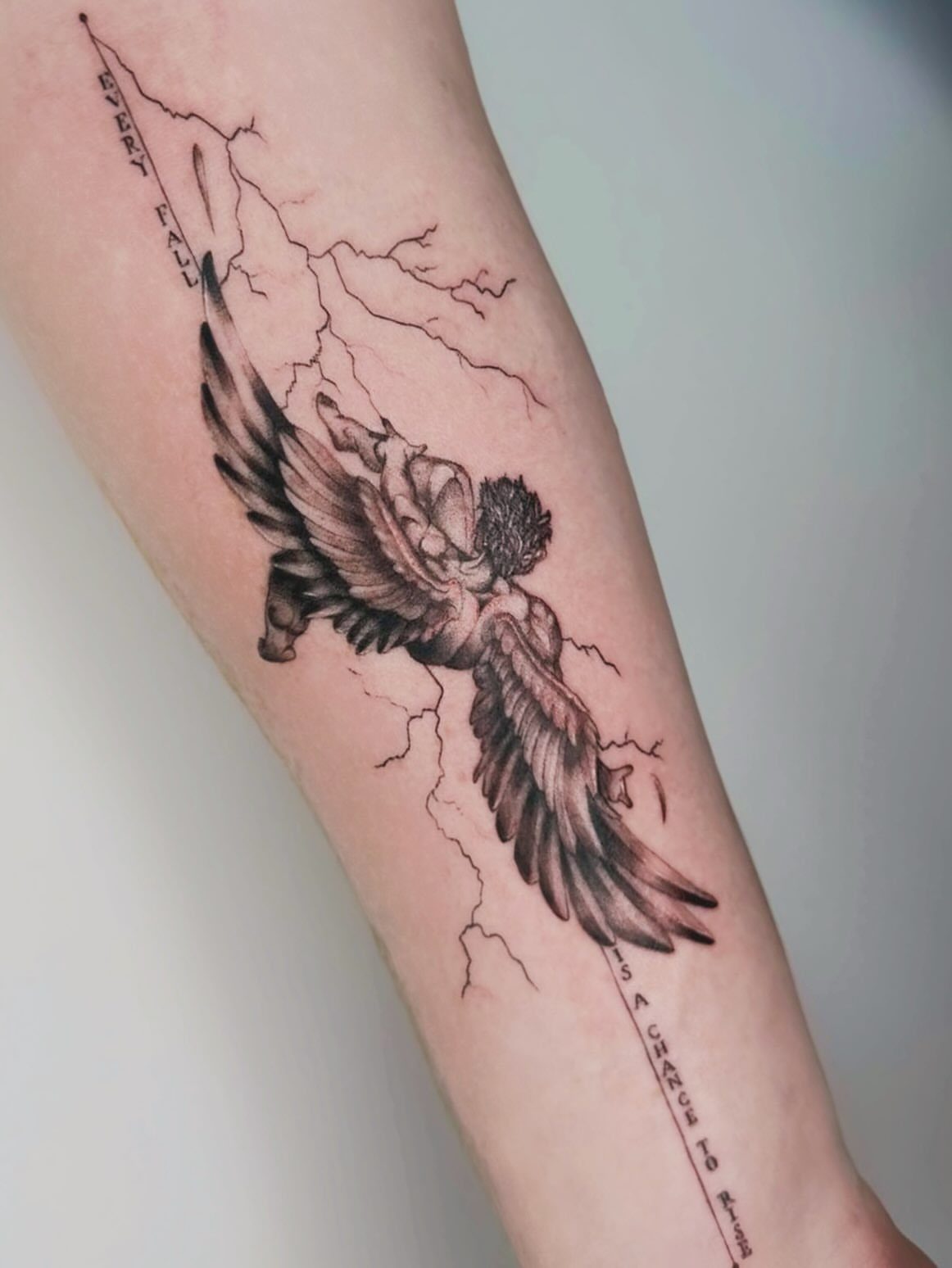 Falling angel tattoo on a forearm with lightning bolts and inspirational text.