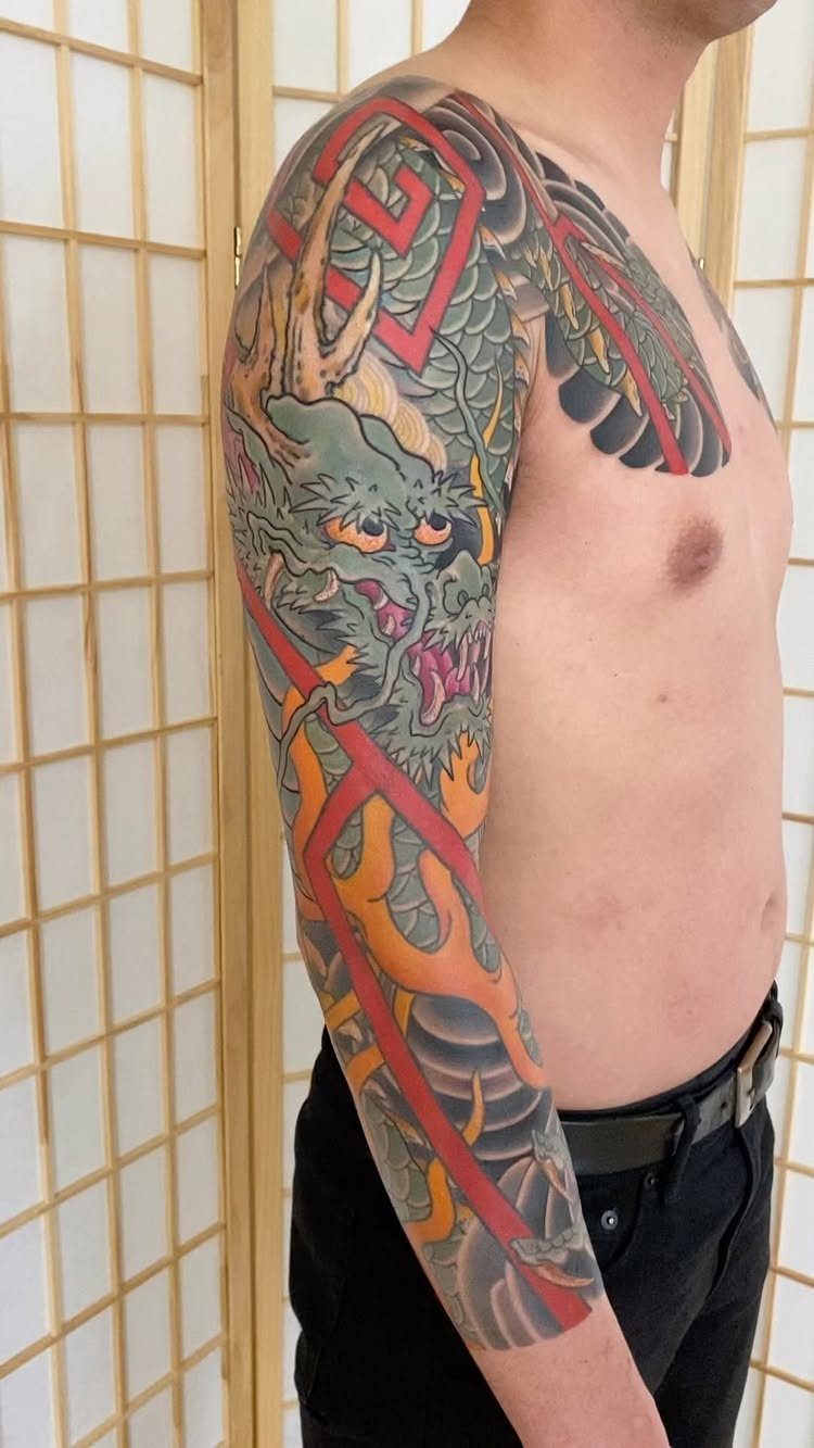 Japanese dragon tattoo on a man's arm with red geometric accents and shading