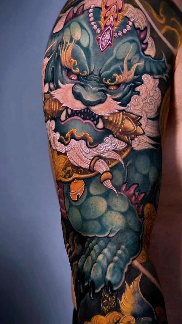 Japanese Foo Dog tattoo on an arm with blue and gold details