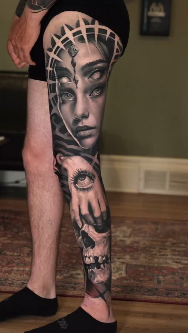 Surreal black and grey realism tattoo of a face and skull on a leg