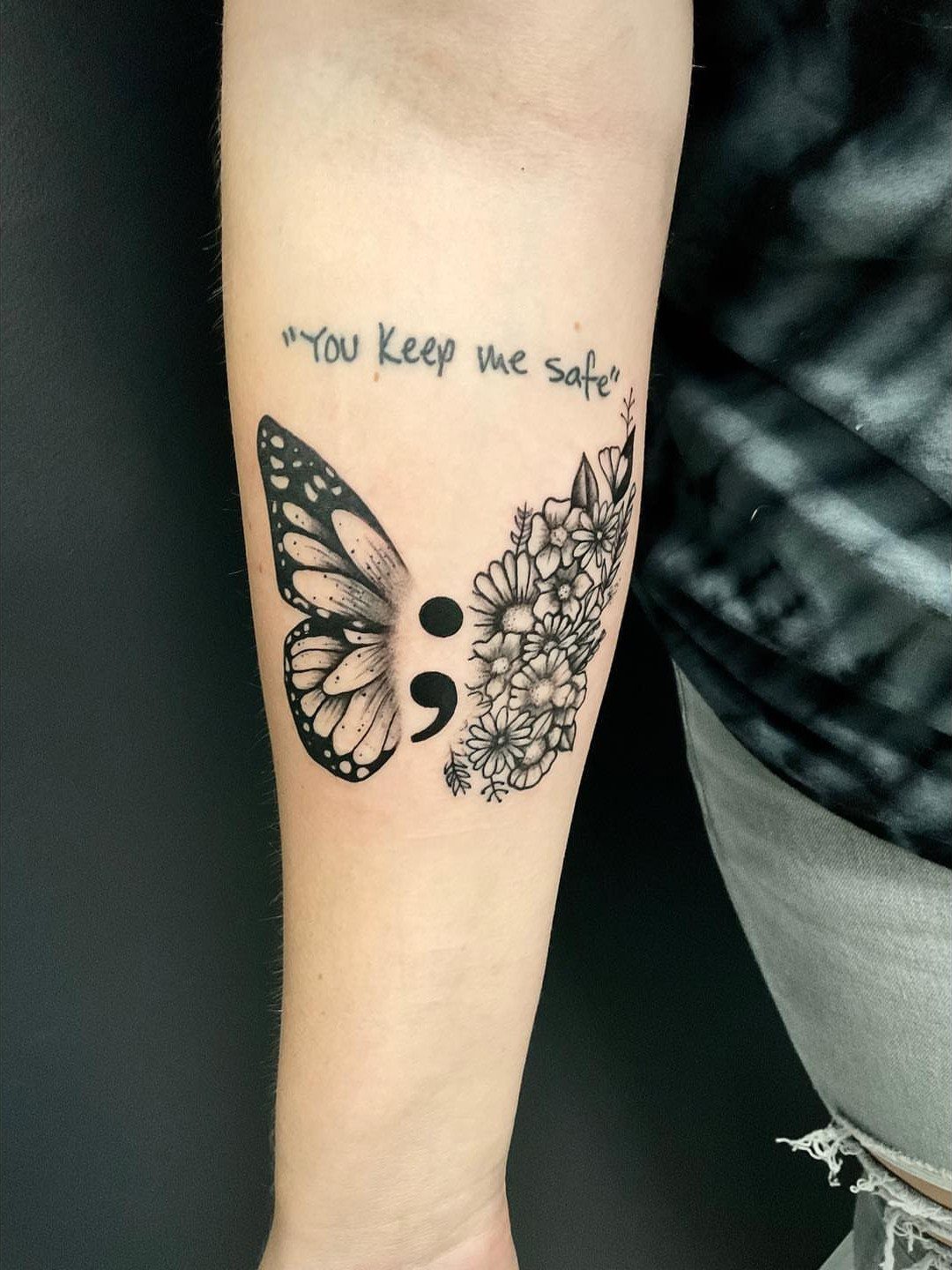 Butterfly semicolon tattoo on forearm with floral wing and the phrase You keep me safe