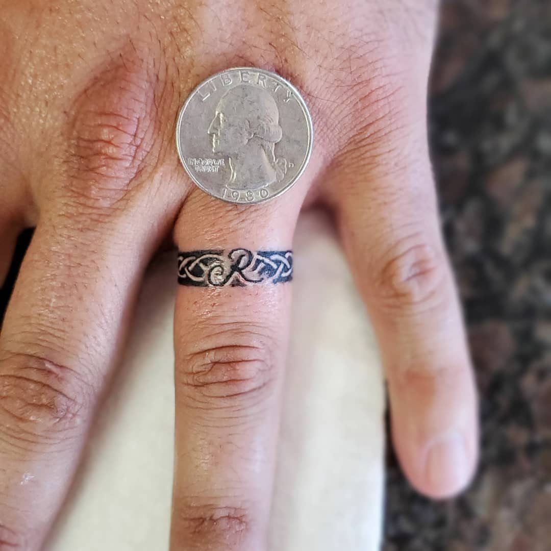 Celtic knot tattoo wrapped around a finger with a quarter coin on top