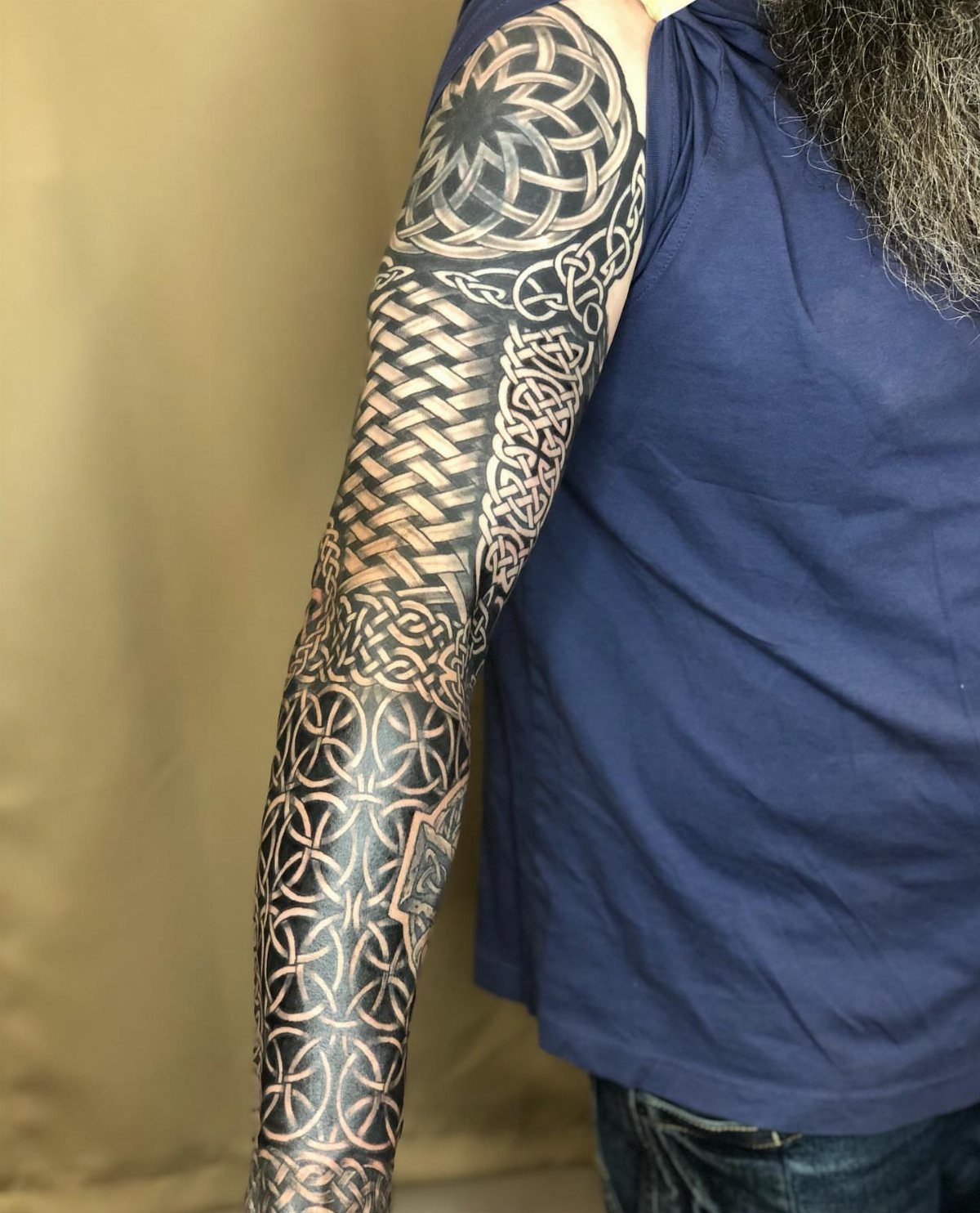 Full sleeve Celtic knot tattoo on a man's arm with intricate black ink patterns.