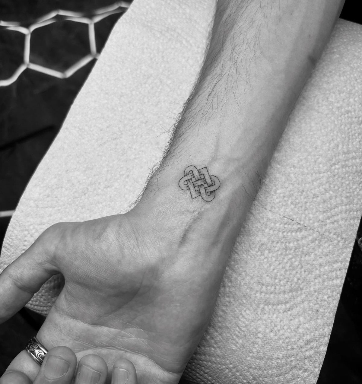 Celtic love knot tattoo on a person's inner wrist resting on a towel