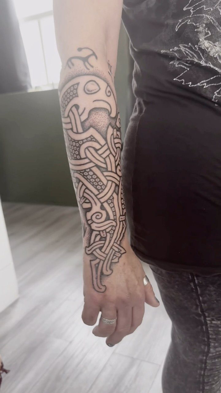Celtic knot tattoo with intricate black ink patterns on a person's forearm