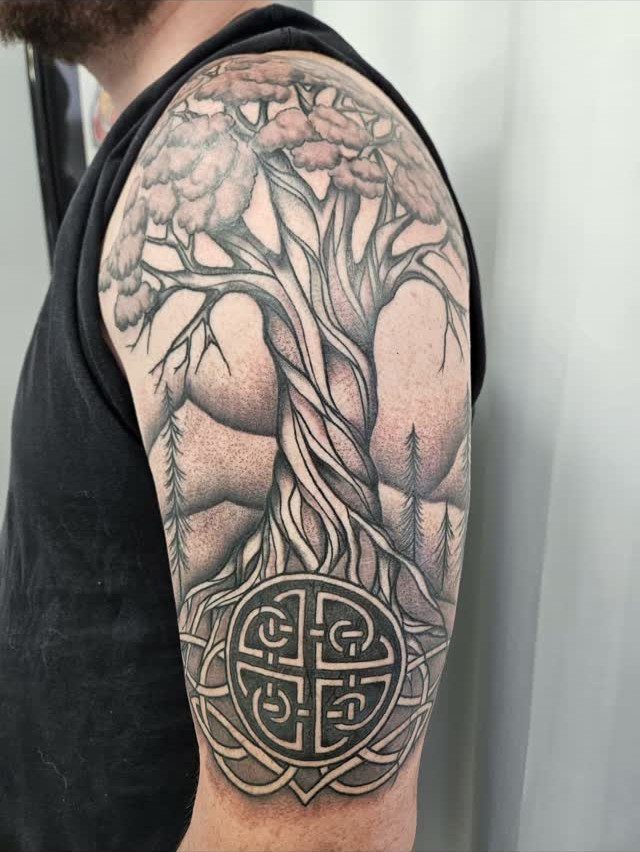 Tree of life tattoo on an upper arm with a Celtic knot base