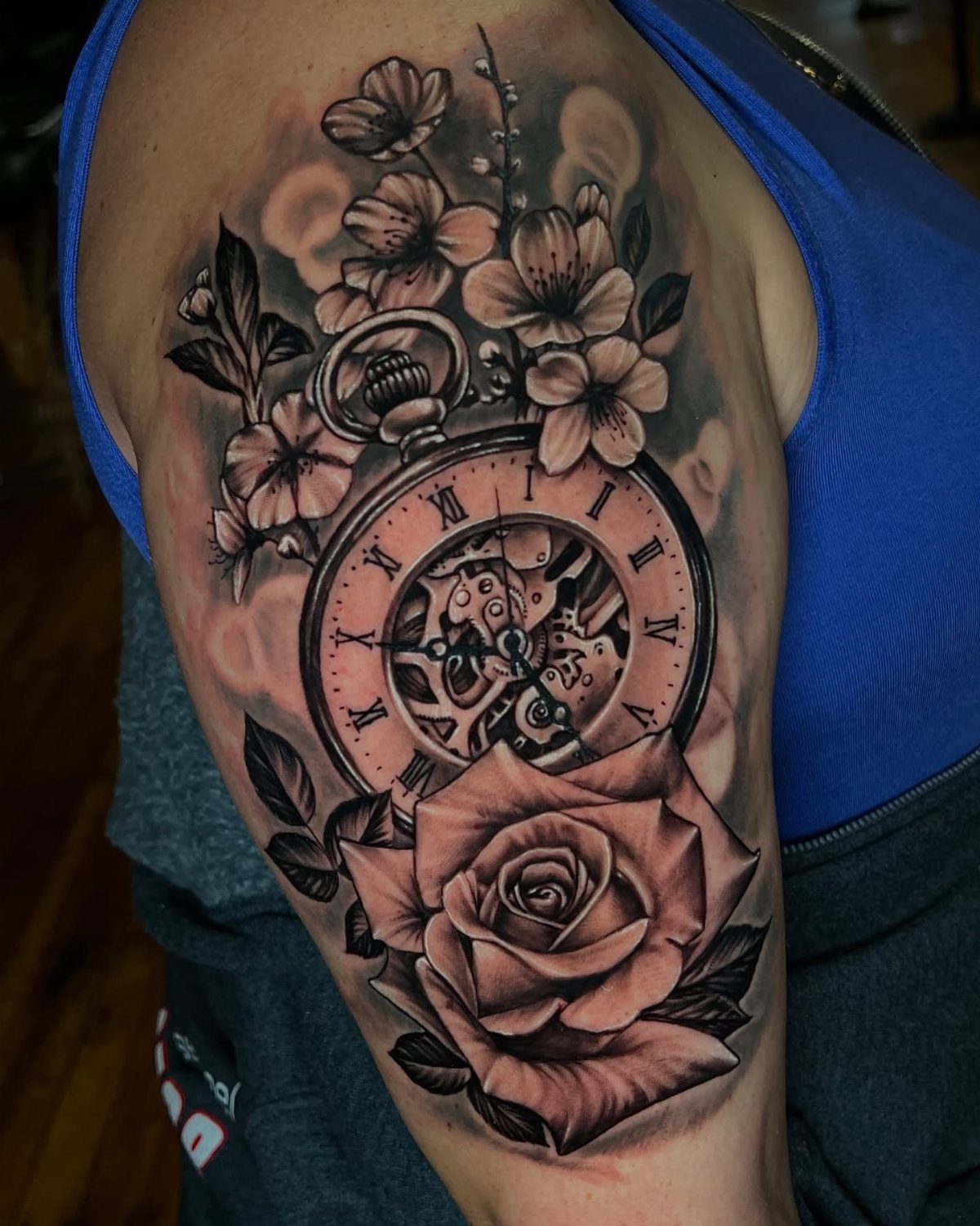 Black and grey tattoo of a pocket watch with cherry blossoms and a rose.