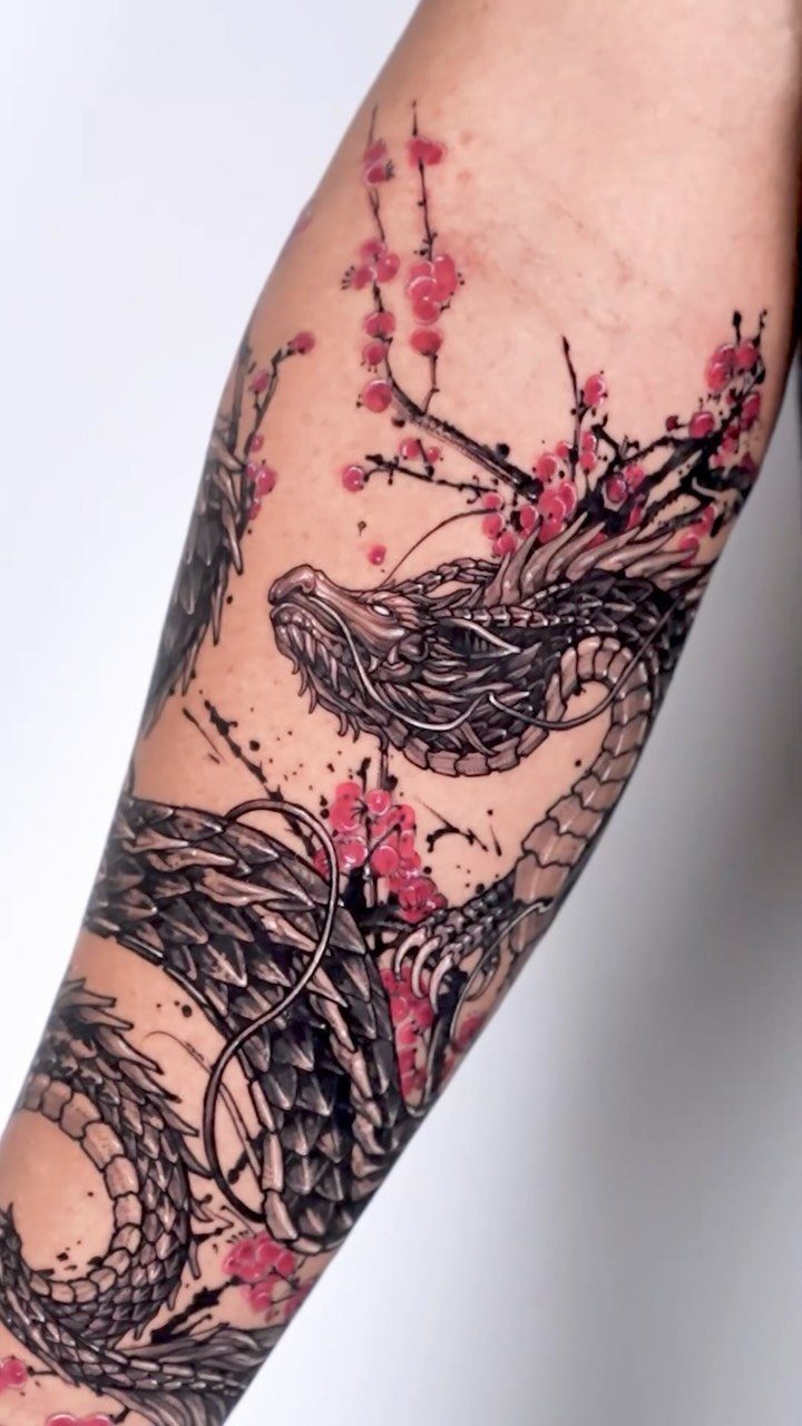 Dragon tattoo with pink cherry blossoms on a person's forearm