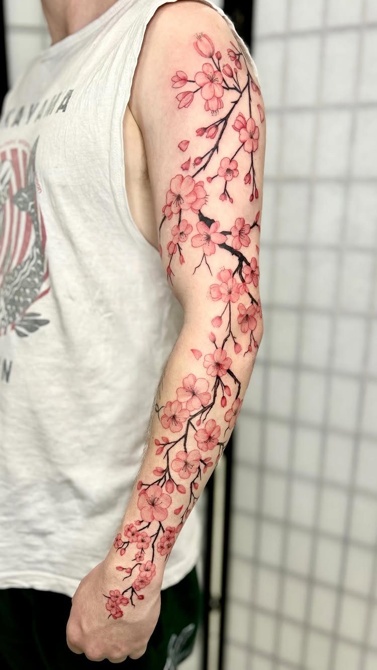 Cherry blossom branch tattoo extending from shoulder to wrist on a person's arm