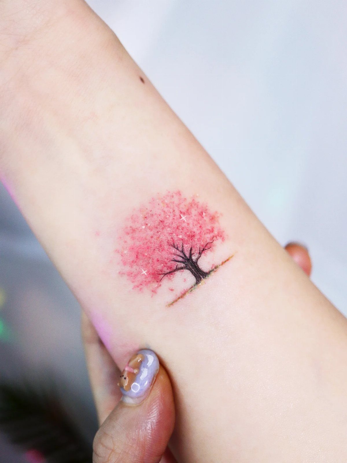 Cherry blossom tree tattoo with pink flowers on a person's inner wrist