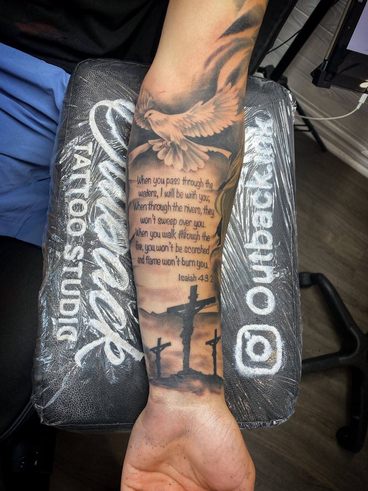 Dove tattoo with biblical scripture and three crosses on a person's forearm sleeve.