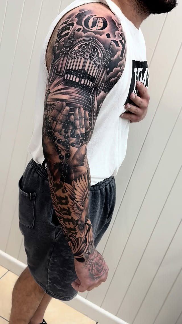 Full sleeve tattoo featuring praying hands with rosary beads and a church gate.