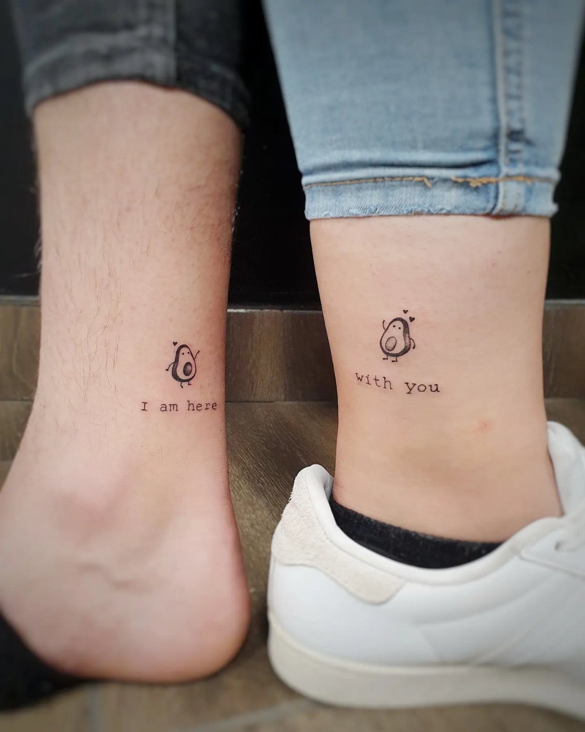 Two ankles with matching avocado tattoos and complementary text phrases.