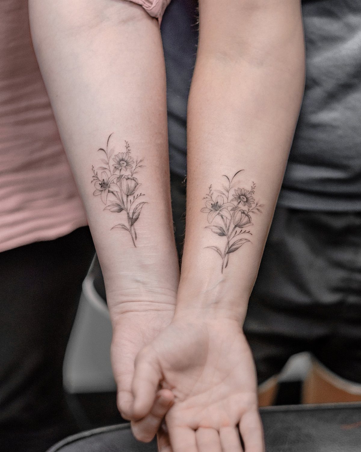 Two matching floral tattoos of flower bouquets on the inner wrists of a couple.