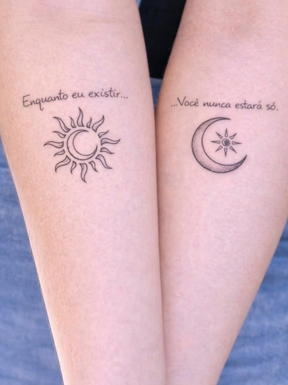 Two forearms with matching sun and moon tattoos and Portuguese text above them.