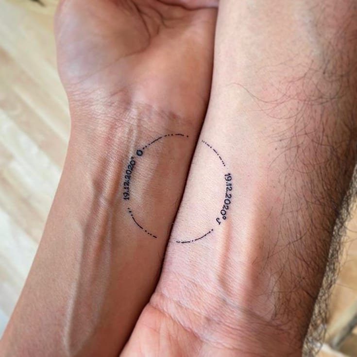 Two wrists with matching date tattoos and dotted lines forming a complete circle.