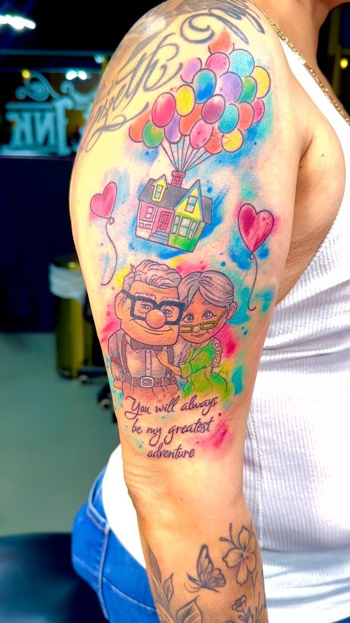 Watercolor tattoo of an elderly couple and a floating house on an arm.