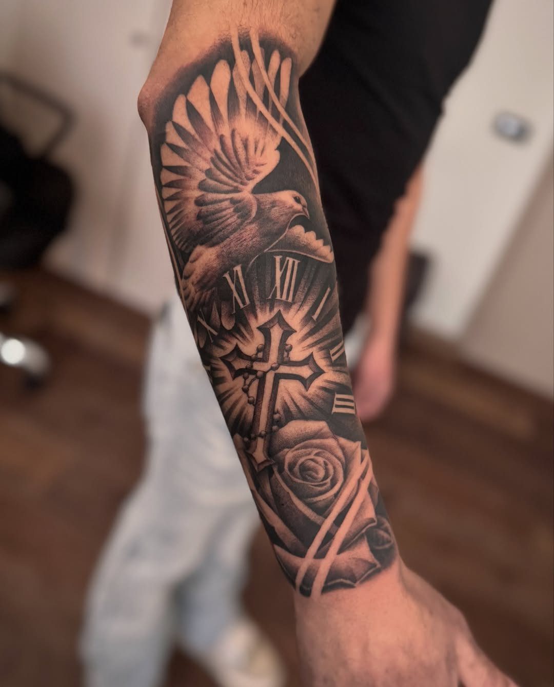 Forearm tattoo featuring a 3D cross, a flying dove, and a blooming rose.