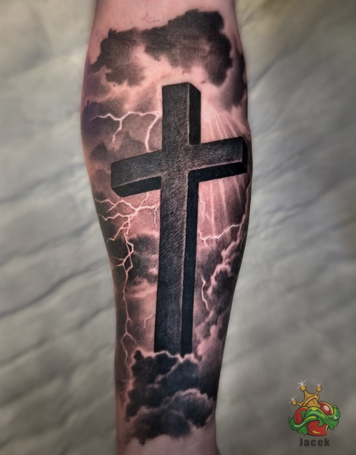 3D cross tattoo on an arm surrounded by dark clouds and lightning bolts