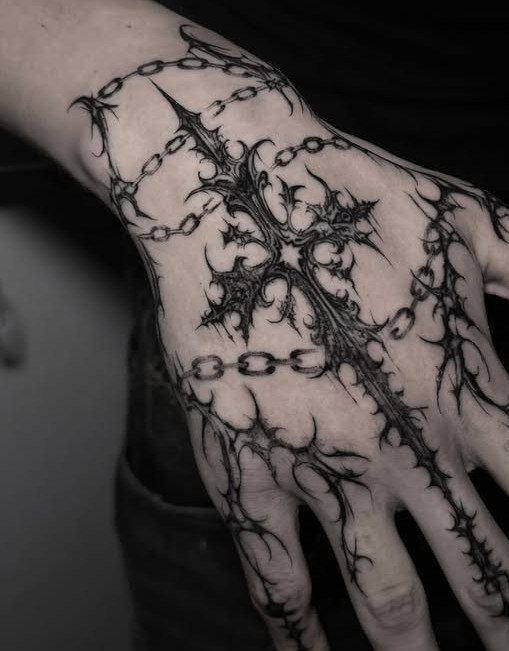 Ornate gothic cross tattoo with chains and thorns on a man's hand