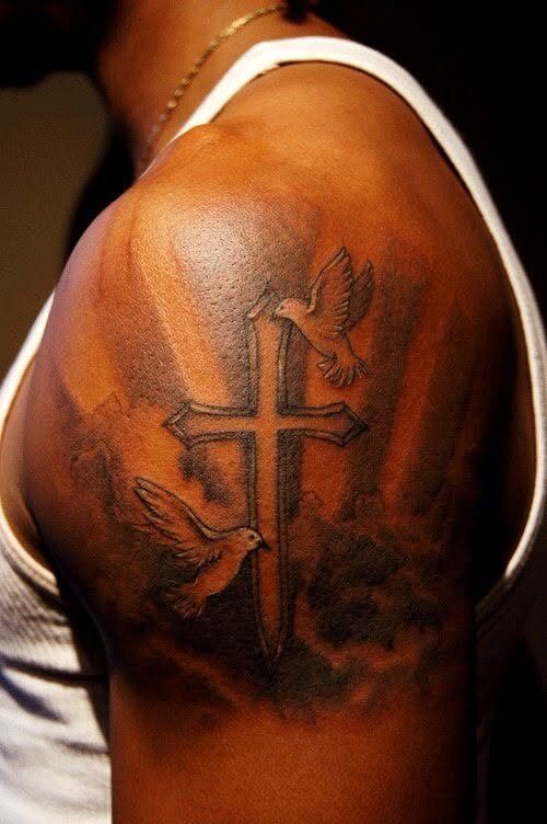 Cross tattoo with two doves and clouds on a man's shoulder