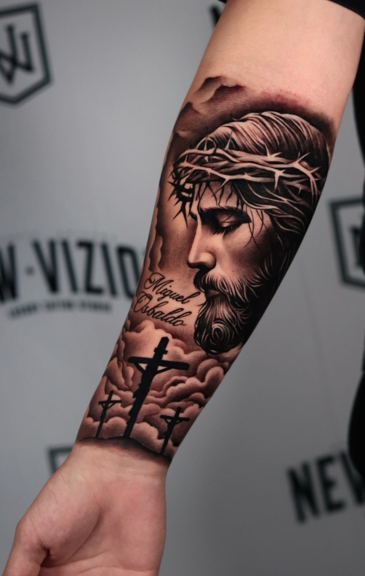 Forearm tattoo of Jesus with crown of thorns and three crosses on hill