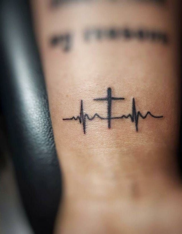 Heartbeat EKG line tattoo with a small black cross on an inner wrist