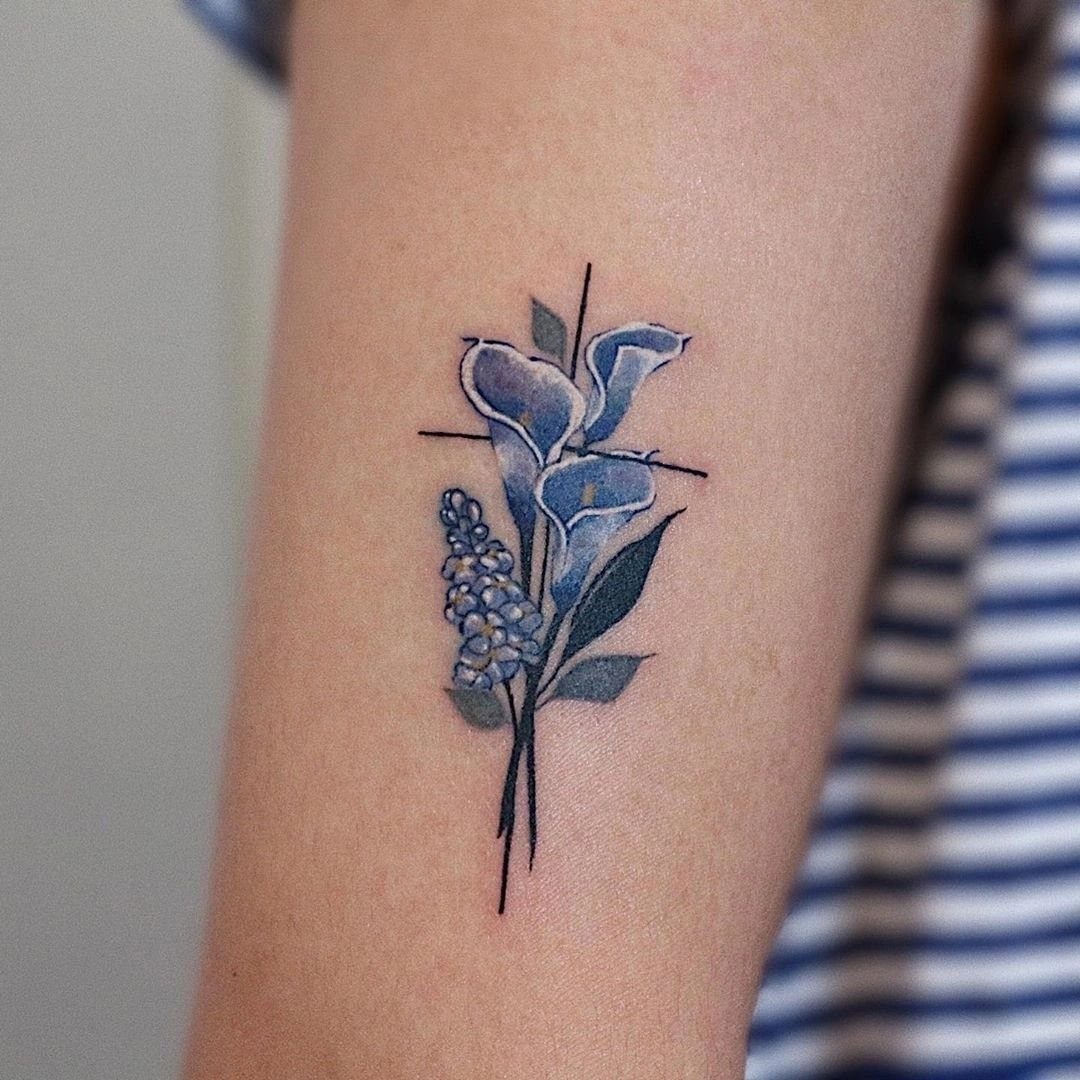 Blue calla lily and flower tattoo shaped like a cross on a forearm