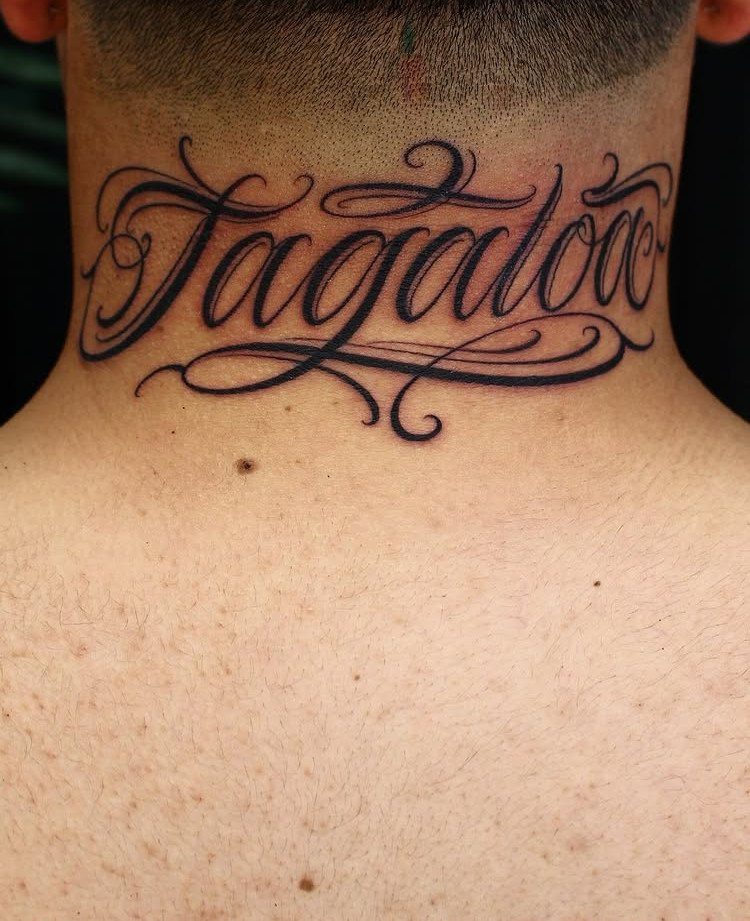 Ornate cursive name tattoo reading Tagaloa on the back of a person's neck