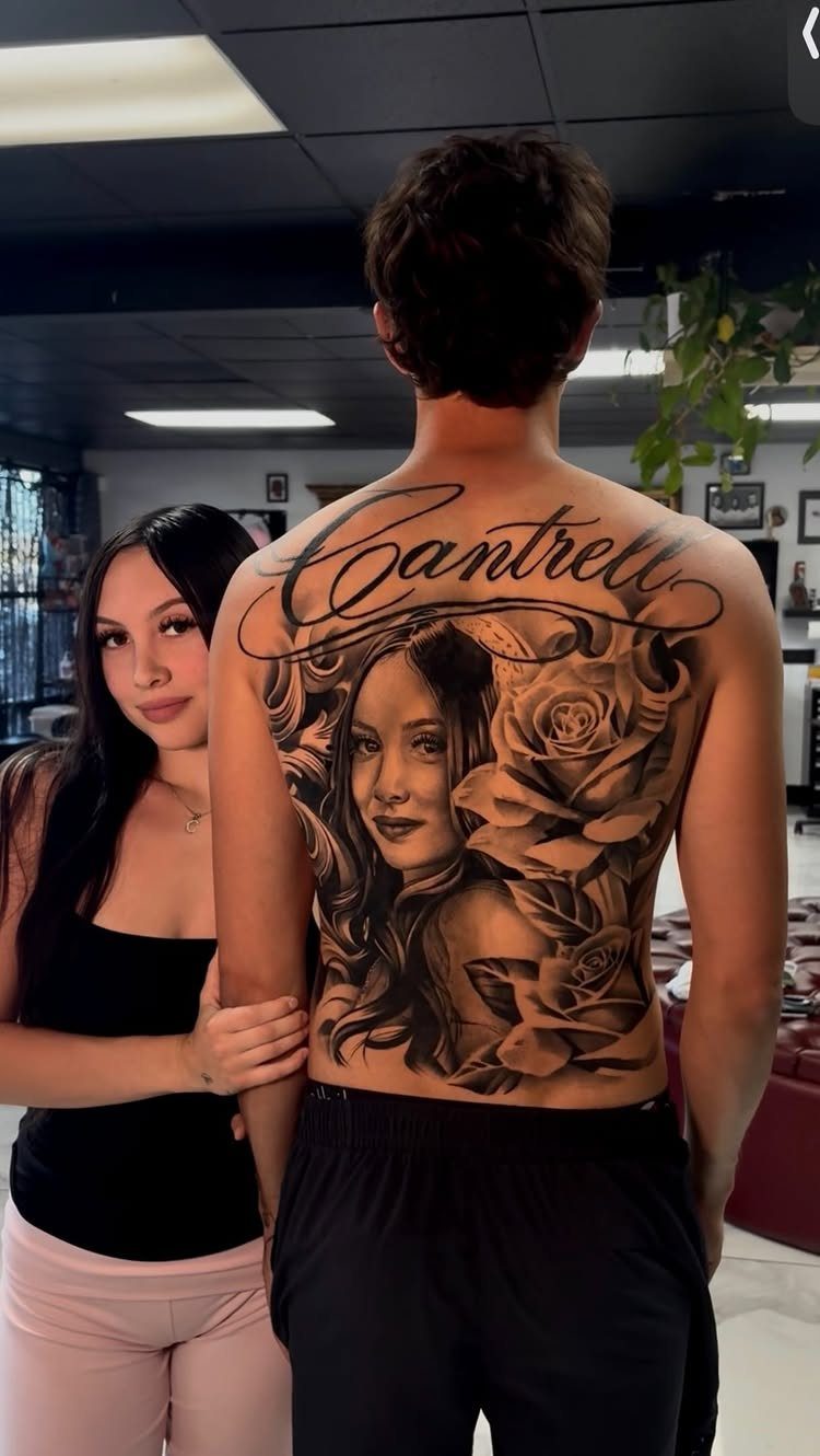 Man's back tattoo featuring a woman's portrait, roses, and the name Cantrell in script.