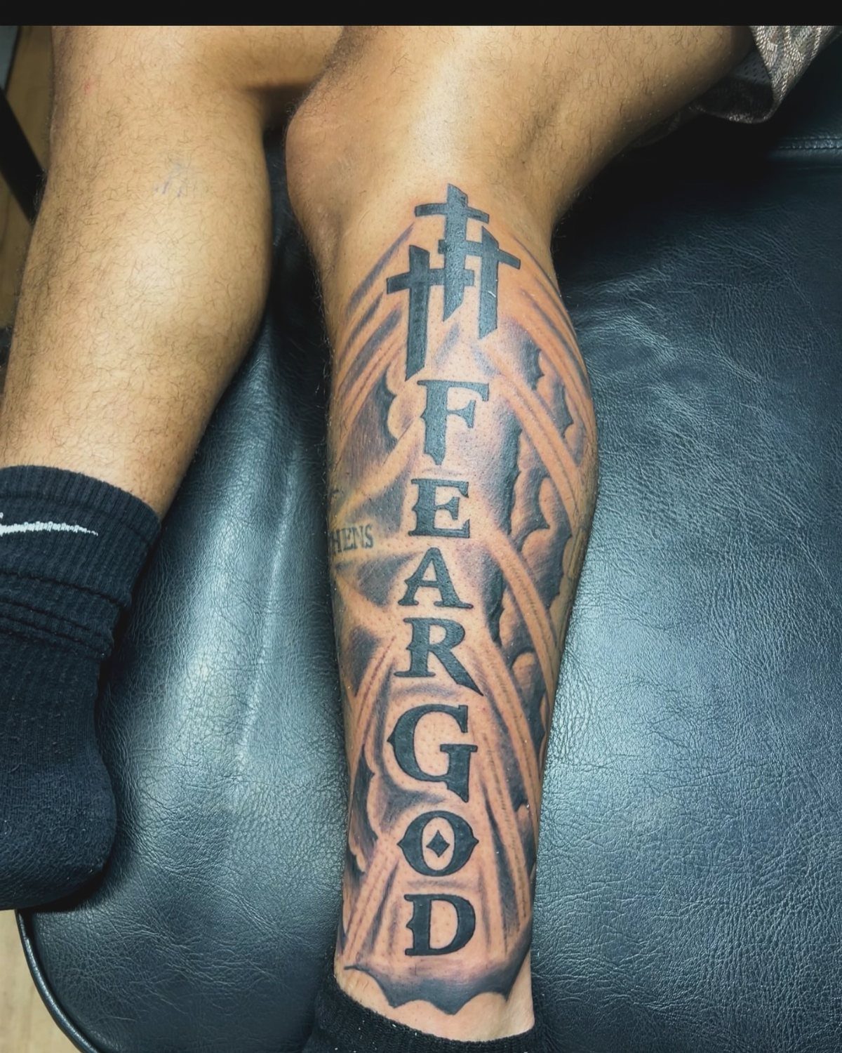 Lower leg tattoo with the words Fear God and religious cross symbols.