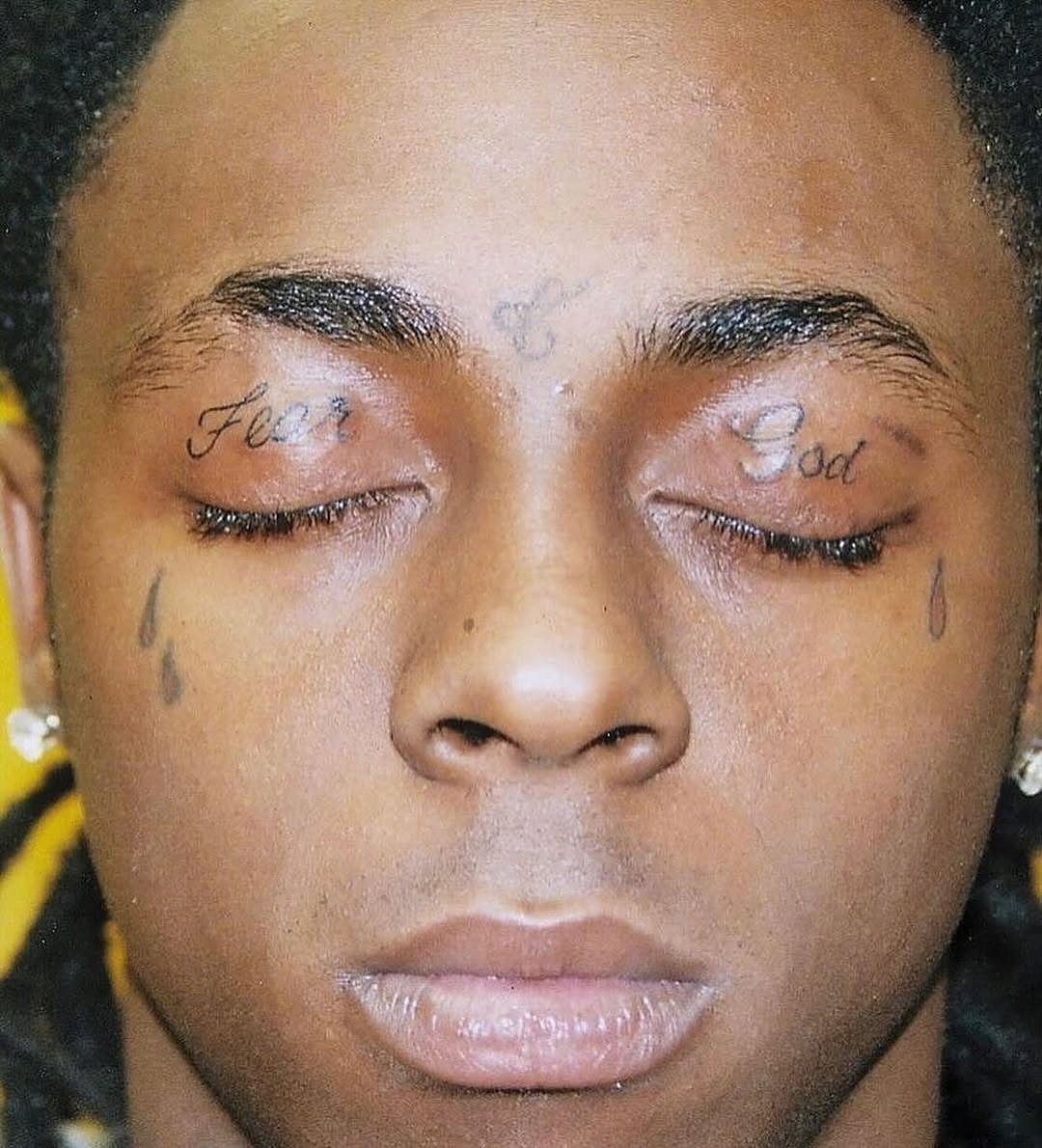 Man's face with Fear God tattoos on eyelids and teardrop tattoos under eyes