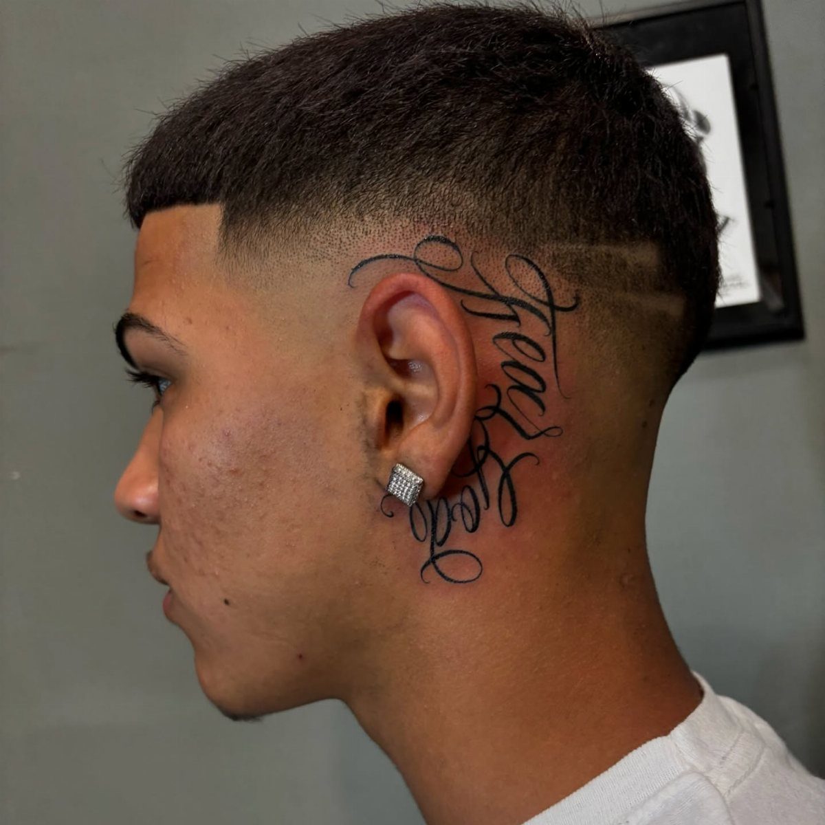 Man with a cursive Fear God tattoo on the side of his neck.
